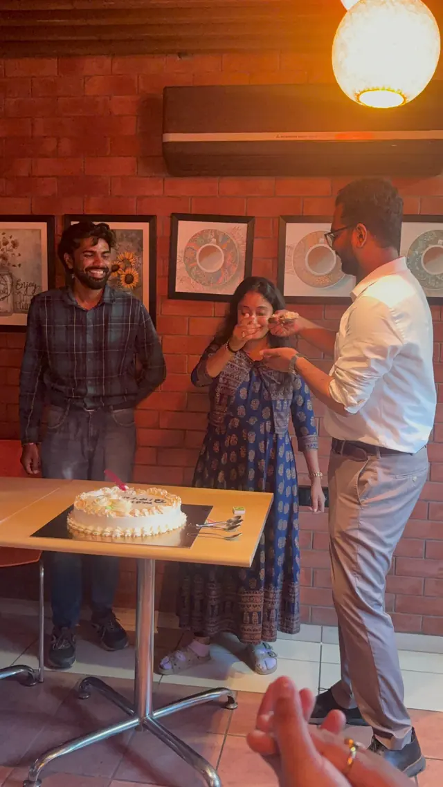 A team celebration with a cake, as one colleague offers another a bite.