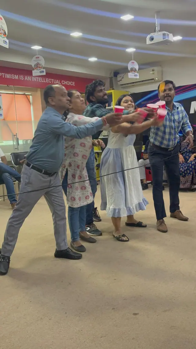 Five colleagues stretch their red cups together to pass a ball down the line.